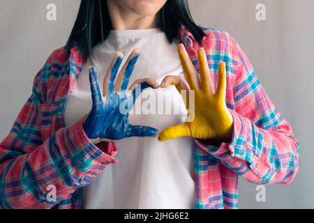 Die Hände der Frau sind auf die Farben der ukrainischen Flagge gemalt. Frieden für die Ukraine. Beenden Sie den Krieg in der Ukraine. Das Konzept der Ukraine gefällt mir sehr gut. Gelb und blau. Weibliche Hände in einer Form o Stockfoto