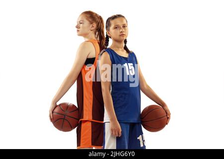 Porträt von zwei jungen Mädchen, Basketballspieler posieren mit Basketballball isoliert auf weißem Hintergrund. Konzept von Sport, Team, wütend, Wettbewerb Stockfoto