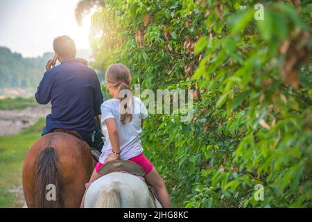 Niedliche kleine kaukasische Mädchen Reiten auf einem kleinen Pony in der chinesischen Landschaft Stockfoto