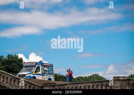 London, UK - June 2020 : Mann und Frau essen im Sommer Eis, das sie von einem Eiswagen gekauft haben, der auf einer Treppe im Crystal Palace Park geparkt ist Stockfoto