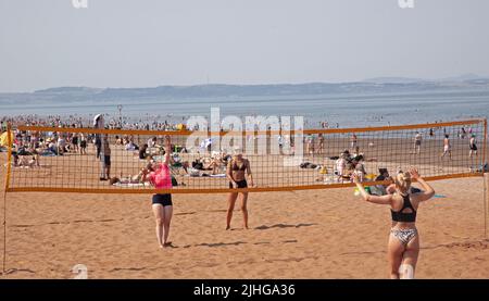 Portobello Seaside, Edinburgh, Schottland, Großbritannien. 18.. Juli 2022. Thermometer, die in Edinburgh eine Temperatur von 30 Grad Celsius anzeigen, aber diese jungen Damen, die am belebten Sandstrand immer noch Volleyball spielen, nicht verhindern. Kredit: Newsandmore/alamy Live Nachrichten. Stockfoto