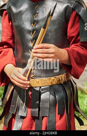 Ein alter römischer Krieger in Vintage-Lederkleidung hält Ballista-Pfeile in der Hand. Rekonstruktion der militärischen Ereignisse während des Krieges der römischen E Stockfoto