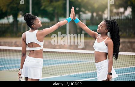 Glückliche Freunde hoch fünf auf dem Tennisplatz. Zwei professionelle Tennisspieler motivieren sich nach einem Spiel. afroamerikanische Mädchen verbinden sich Stockfoto