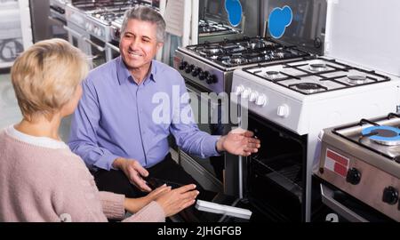 Mann und Frau 47-55 Jahre alt kaufen in der Mitte der Haushaltsgeräte den Teller Stockfoto
