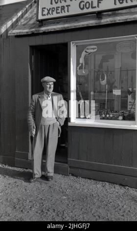 1950s, historisch, stehend in seiner Jacke und Krawatte und Stoffkappe vor seinem Geschäft, schottischer Golfprofi und Golfclubhersteller, Tom Reekie von Elie Golf Club, Fife, Schottland, Großbritannien. Geboren 1880 in St.Monans, nahm Tom 1895 eine Lehre und arbeitete bei dem Golfclub-Hersteller George Forrester in Earlsferry, wo er bis zu seiner Dienstzeit WW1 arbeitete. Nachdem er den Krieg überlebt hatte, gründete er 1919 sein eigenes Geschäft als Golfprofi und Clubmacher bei Elie und 1946 wurde es Tom Reekie & Son, als sein Sohn John zu ihm kam Stockfoto