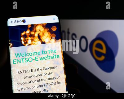Person mit Mobiltelefon und Website des europäischen Energieverbands ENTSO-E auf dem Bildschirm vor dem Logo. Konzentrieren Sie sich auf die Mitte des Telefondisplays. Stockfoto