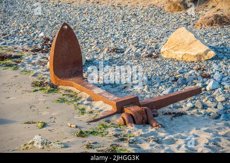 Gerettete rostige Schiffswrackboote ankern teilweise im Sand an einem felsigen Kiesstrand vergraben vom Meeresboden Stockfoto