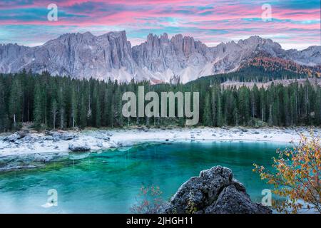 Malerischer Blick auf den gefrorenen Karersee in der Provinz Bozen - Südtirol. Rosafarbener Sonnenaufgang in den italienischen Dolomiten. Landschaftsfotografie Stockfoto