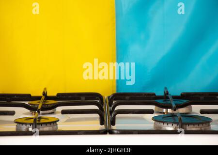 Die ukrainische Flagge hängt an der Wand in der Küche in einer Wohnung in der Ukraine vor dem Hintergrund eines Gasofens, des Krieges in der Ukraine, ohne Gas Stockfoto