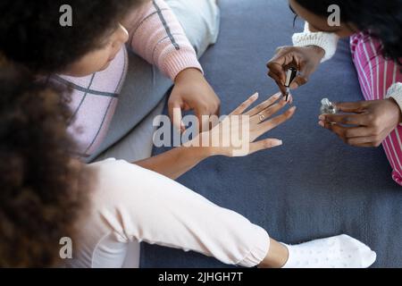High-Angle-Ansicht der biracial junge Frau Malerei Fingernägel einer Freundin auf dem Bett zu Hause Stockfoto