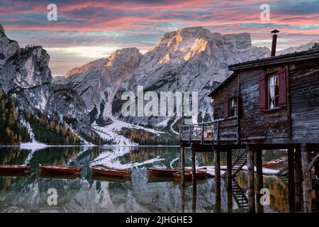 Malerische Landschaft mit dem berühmten Pragser See in den herbstlichen Dolomitenbergen. Holzboote und Pier im klaren Wasser des Pragser Sees, Dolomiten-Alpen, Italien. Seekofel Berggipfel im Hintergrund Stockfoto