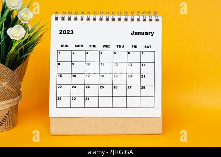 Weißer Kalender Januar 2023 mit Topfpflanze auf gelbem Hintergrund. Stockfoto