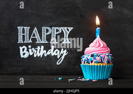 Geburtstagskuchen mit Geburtstagskerze vor der Tafel mit Glückwünsche zum Geburtstag Stockfoto