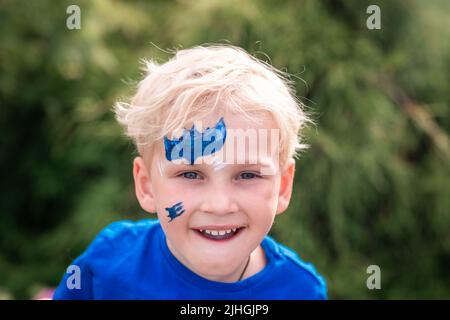 Niedlicher kleiner Junge mit Gesichtsfarbe mit batman-Muster. Gesichtsbemalung, Kindergesicht auf der Geburtstagsfeier Stockfoto