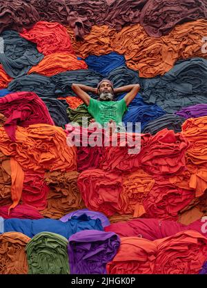 Bunte Decken werden von Arbeitern auf LKWs geladen. Textilindustrie in Bangladesch Stockfoto