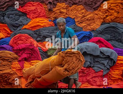 Bunte Decken werden von Arbeitern auf LKWs geladen. Textilindustrie in Bangladesch Stockfoto