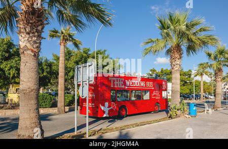 Paphos, Zypern - 29. Okt 2014: Roter Doppeldecker der Hochzeitsbus mit Gästen auf der Fahrt zwischen Palmen in der schönen und ruhigen Stadt paphos, Zypern - Traumhochzeit-Destination Stockfoto