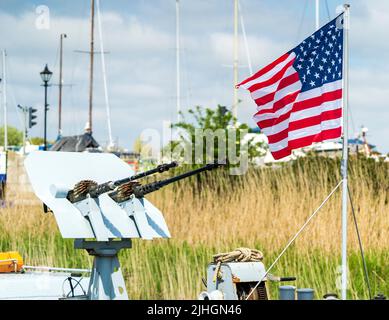 Amerikanische Flagge flattert im Wind neben einem M1919 Browning-Geschützturm auf dem Bug-Deck des US Navy-Patrouillenbootes P22 in Sandwich. Stockfoto