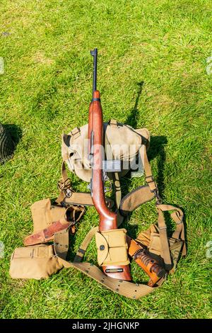 Ausrüstung der US-Armee im zweiten Weltkrieg, die auf Gras liegt. M1 Karabinergewehr, Gürtel, Messer, Pack- und Munitionspackungen. Stockfoto