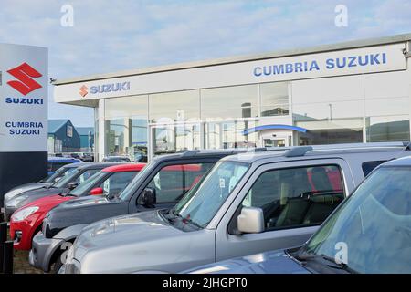 Vorplatz von Cumbria Suzuki, auf dem verschiedene Suzuki-Autos vor modernen Auto-Showrooms zum Verkauf stehen. Stockfoto