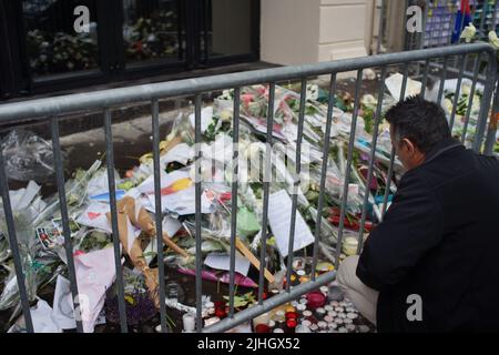 Der Mann sieht Blumen, Kerzen und Botschaften vor der Pariser Musikhalle von Bataclan an, um an die Opfer der Pariser Anschläge vom 2015. November zu erinnern. Le Bataclan, 50 Boulevard Voltaire, Paris, Frankreich - Pariser Terroranschläge - ein Jahr darauf Stockfoto