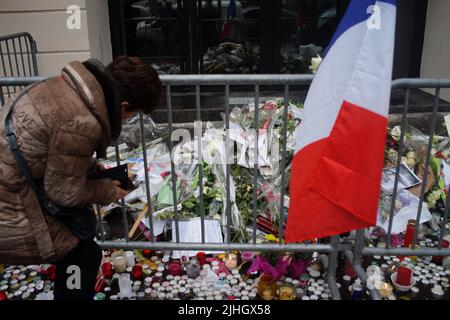 Eine Frau steht vor Blumen, Kerzen, Botschaften und Fotos, um an die Opfer der Pariser Anschläge vom 2015. November zu erinnern. Le Bataclan Music venue, 50 Boulevard Voltaire, Paris, Frankreich - Paris greift an - ein Jahr nach dem Stockfoto