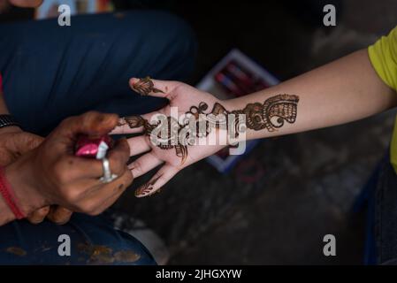 Kathmandu, Nepal. 18.. Juli 2022. Während des Festivals schmückt ein Künstler die Hand eines nepalesischen Anhängers mit Mehendi (Henna). Während des Monats Shrawan beten nepalesische Hindu-Frauen jeden Montag Lord Shiva für ein langes und wohlhabendes Leben für ihren Ehemann an oder um einen guten zu erhalten. Kredit: SOPA Images Limited/Alamy Live Nachrichten Stockfoto