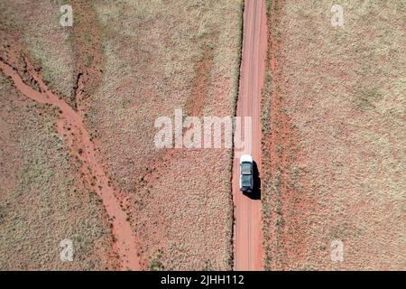 Drohnenaufnahme eines Autos auf einer roten Schotterstraße in Namibia Afrika Stockfoto