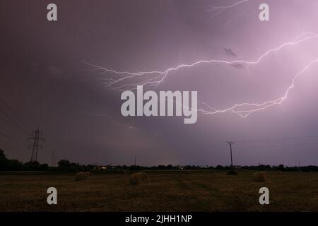 Gewitter über dem Feld mit rollenden Ballen in der Nacht, Blitz in Wolken in der Nacht auf dem Land, Wolke zu Wolke verzweigten Blitz Stockfoto