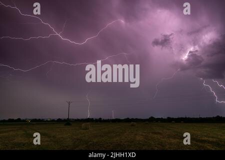 Gewitter über dem Feld mit rollenden Ballen in der Nacht, Blitz in Wolken in der Nacht auf dem Land, Wolke zu Wolke verzweigten Blitz Stockfoto