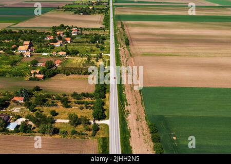 Gerade Asphaltstraße durch ländliche Landschaft mit wenigen Autos fahren in beide Richtungen, Luftaufnahme von Drohne pov Stockfoto