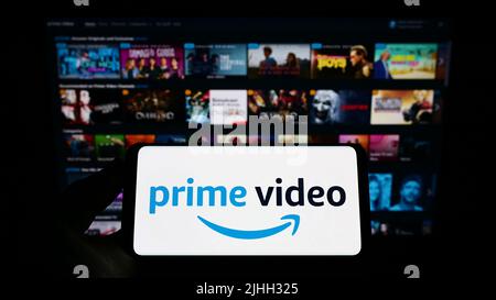 Person, die das Smartphone mit dem Logo des Streaming-Dienstes Amazon Prime Video auf dem Bildschirm vor der Website hält. Konzentrieren Sie sich auf die Telefonanzeige. Stockfoto