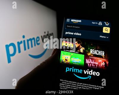 Person, die Mobiltelefon mit der Webseite des Streaming-Dienstes Amazon Prime Video auf dem Bildschirm vor dem Logo hält. Konzentrieren Sie sich auf die Mitte des Telefondisplays. Stockfoto