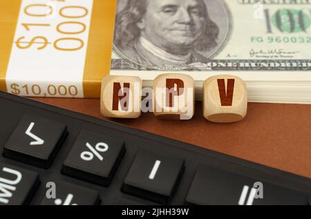 Business concept. On the table are dollars, a calculator and cubes with the inscription - NPV Stockfoto