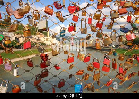 Makartsteg-Brücke in Salzburg (Love Lock Bridge). Der Blick auf den Fluss und das Stadtpanorama durch den Schleusenzaun. 30. Juni 2022. Stockfoto