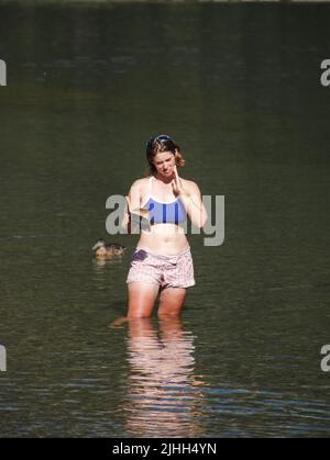 See Roto-iti Neuseeland - Februar 17 2007; Frau steht im Wasser und kühlt sich ab, während sie Buch liest Stockfoto