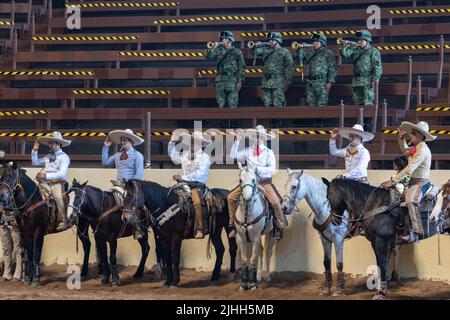 Mexikanische Soldaten spielen die Nationalhymne, während Rodeo-Fahrer während der Staatlichen Meisterschaft Charreria in Rancho El Pitayo am 3. April 2022 in Tlacote el Bajo, Queretaro, Mexiko, in Aufmerksamkeit stehen. Charreria ist die mexikanische Rodeo-Veranstaltung mit Pferd und Stier Reiten Wettbewerbe. Quelle: Richard Ellis/Richard Ellis/Alamy Live News Stockfoto