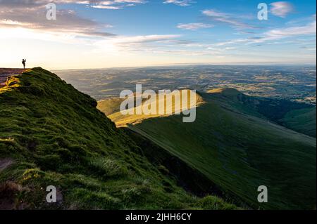 Blick auf einen Mann, der auf einem Berg Fotos gemacht hat, der die Nachrichten bei PEN y Fan brecon Beacons im Süden von wales, großbritannien, aufgenommen hat Stockfoto