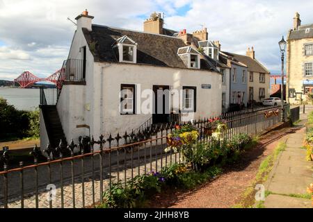 Schottische Stadt, malerisches weißes Haus in einer Kopfsteinpflasterstraße mit der Forth Bridge im Hintergrund, South Queensferry, Schottland, Großbritannien Stockfoto