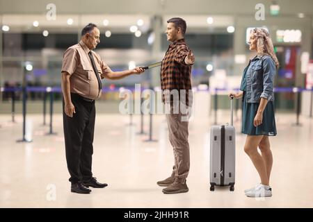 Wachmann überprüft Passagiere mit einem Scanner auf einem Flughafen Stockfoto