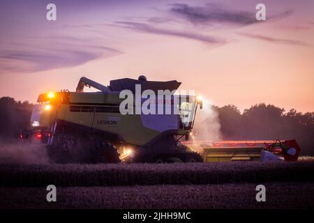 18. Juli 2022, Mecklenburg-Vorpommern, Groß Welzin: Ein Mähdrescher fährt nach Sonnenuntergang über ein Feld, um Weizen zu ernten. Die Landwirte in Norddeutschland nutzen derzeit das trockene Wetter, um Getreide zu ernten. Foto: Jens Büttner/dpa Stockfoto