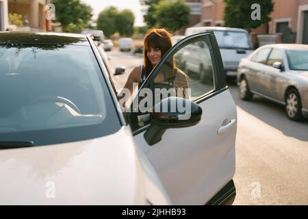 Vorderansicht einer Frau, die in ein Auto einfährt Stockfoto