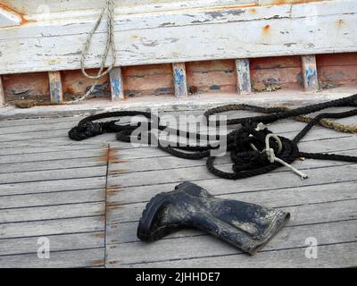 Seile und Gummistiefel auf dem Deck des Fischerbootes Stockfoto