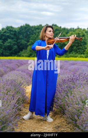 Ganzkörper Erwachsene Frau Geigerin spielt Geige auf Sommer Lavendel Feld Stockfoto