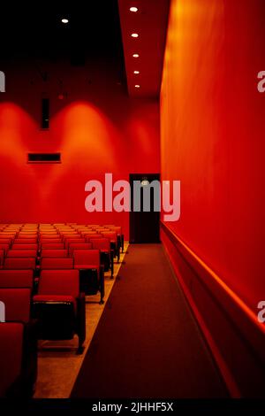 Hellroter Auditorium mit stoffbedeckten Sitzen und Ausstiegsschild Stockfoto