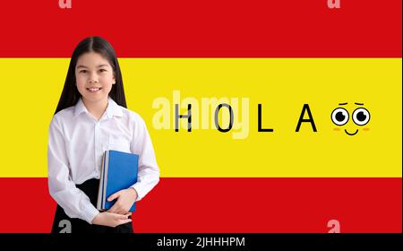 Kleine asiatische Schulmädchen und Wort HOLA (HALLO) gegen Flagge von Spanien Stockfoto