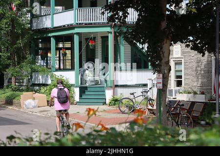 Ein Fahrradfahrer, der an einem von Hunderten von schönen Häusern in der Chautauqua Institution, Chautauqua, NY, vorbeifährt, Juni 2022 Stockfoto