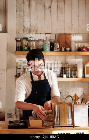 Coffee Shop Barista beim Einchecken hat er genug Tassenhüllen Stockfoto