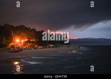 Pilat-Düne, Frankreich, 18. Juli 2022, die Menschen beobachten den Rauch, der am 18. Juli 2022 vom Pier Mouleau in Arcachon im Wald La Teste-de-Buch am Fuße der Pilat-Düne aufsteigt. Fast 13.000 Hektar Land wurden durch die beiden Waldbrände zerstört, die seit fast einer Woche in der Nähe beliebter Ferienorte im südwestlichen Departement Gironde brennen. In ihrem letzten Update gestern Abend (17. Juli) erklärte die Präfektur des Departements, dass 1.500 Feuerwehrleute aus ganz Frankreich gekommen seien, um bei der Bekämpfung der „abnormen“ Brände zu helfen, die in der Gemeinde La Teste-de-Buch in der Nähe der Düne ihren Anfang nahmen Stockfoto