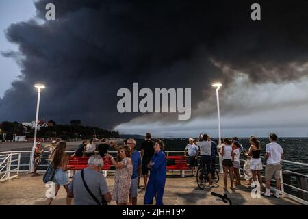 Pilat-Düne, Frankreich, 18. Juli 2022, die Menschen beobachten den Rauch, der am 18. Juli 2022 vom Pier Mouleau in Arcachon im Wald La Teste-de-Buch am Fuße der Pilat-Düne aufsteigt. Fast 13.000 Hektar Land wurden durch die beiden Waldbrände zerstört, die seit fast einer Woche in der Nähe beliebter Ferienorte im südwestlichen Departement Gironde brennen. In ihrem letzten Update gestern Abend (17. Juli) erklärte die Präfektur des Departements, dass 1.500 Feuerwehrleute aus ganz Frankreich gekommen seien, um bei der Bekämpfung der „abnormen“ Brände zu helfen, die in der Gemeinde La Teste-de-Buch in der Nähe der Düne ihren Anfang nahmen Stockfoto